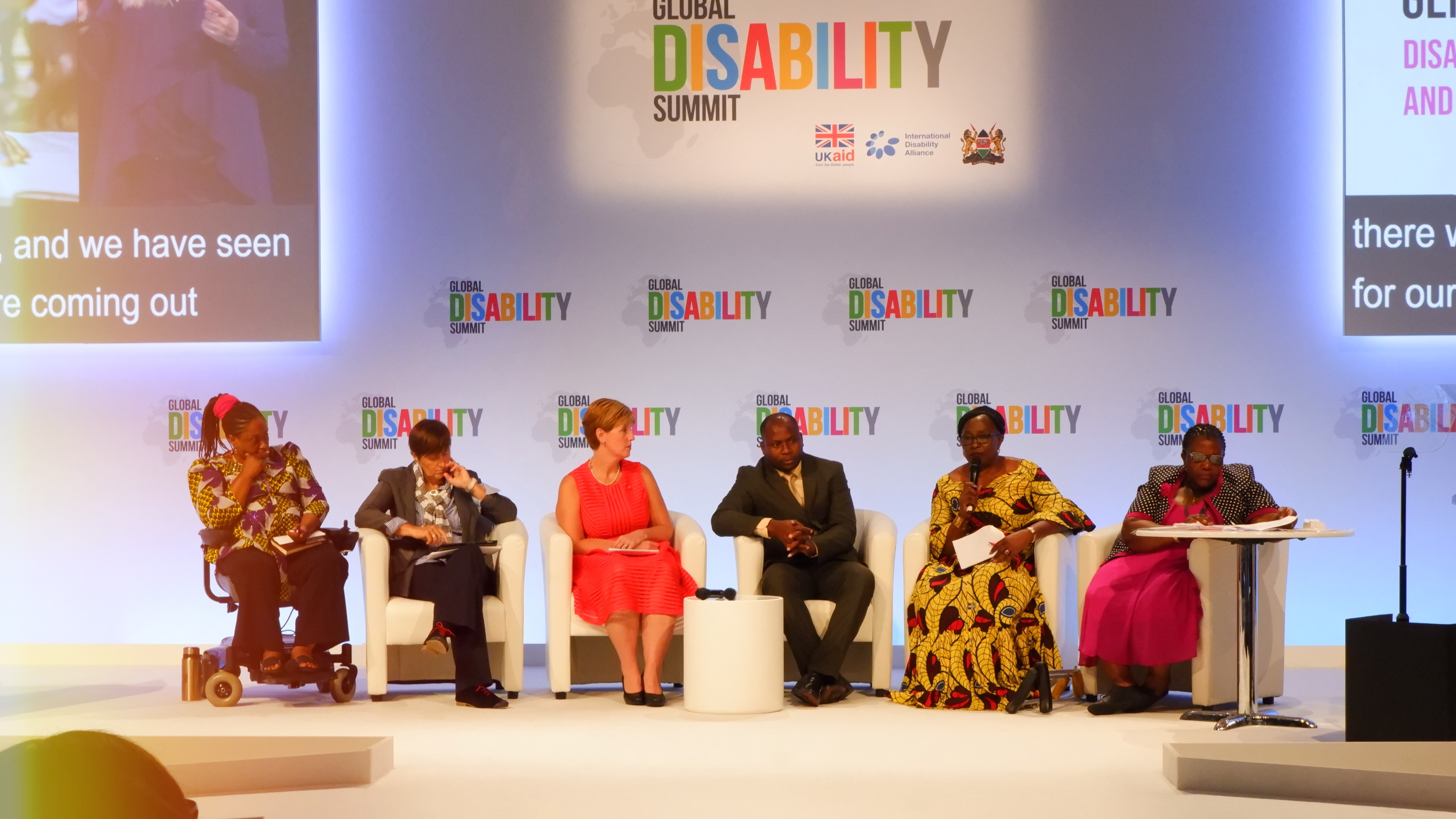 Panellists from GDS 2018 addressing the audience. Panellists from left to right: An african woman on wheelchair, a caucasian woman in a suit, a caucasian woman in a dress, an African man wearing a suit, an African woman with a mic in her hand wearing a traditional African dress, a Blind African woman in traditional attire.