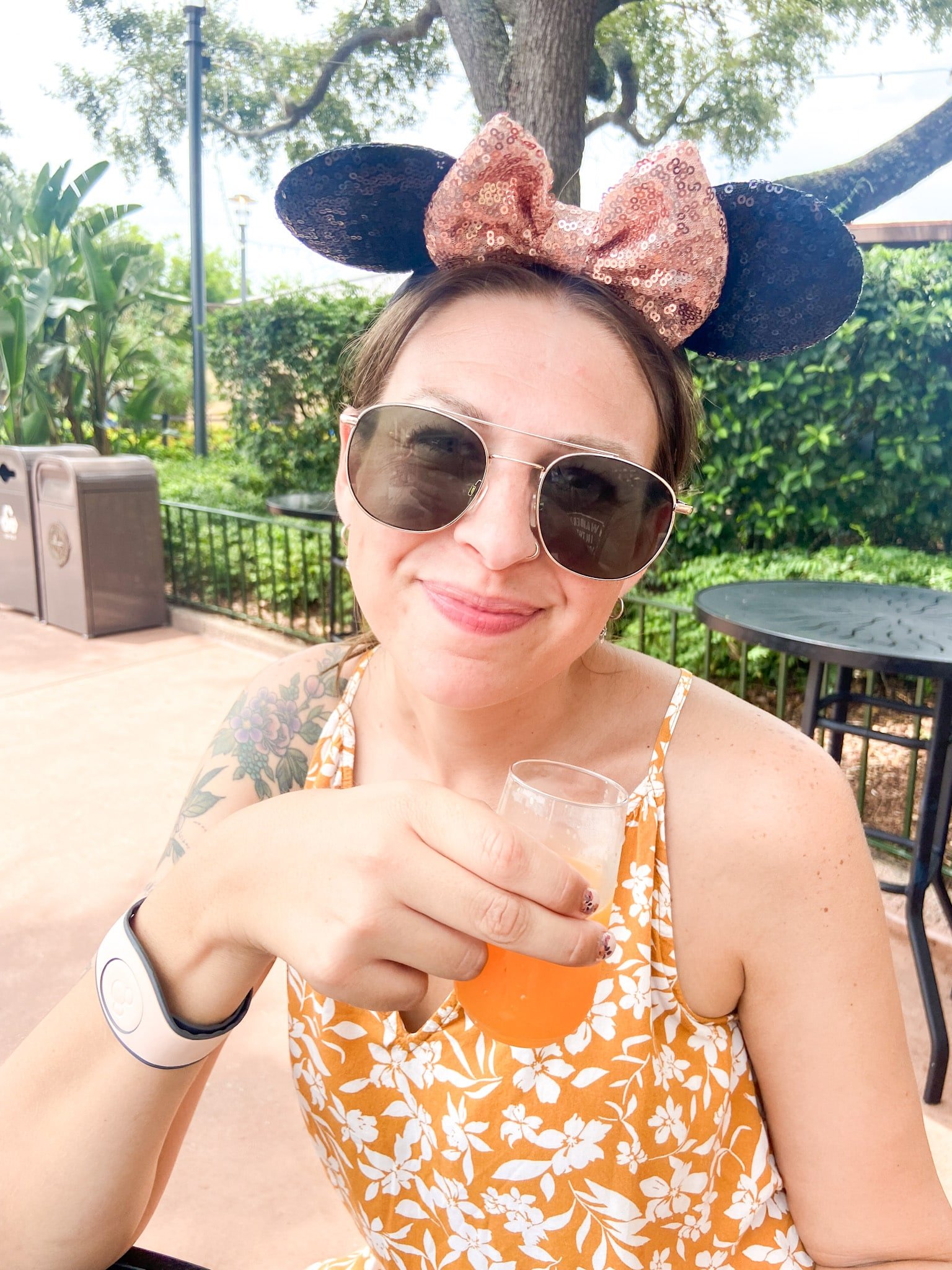 Walt Disney World Travel Expert, a travel agent based in eau claire wisconsin. Alisha with Friend Like Me Travel Co drinks a mimosa in epcot at walt disney world in orlando during the summer. She wears mickey ears.