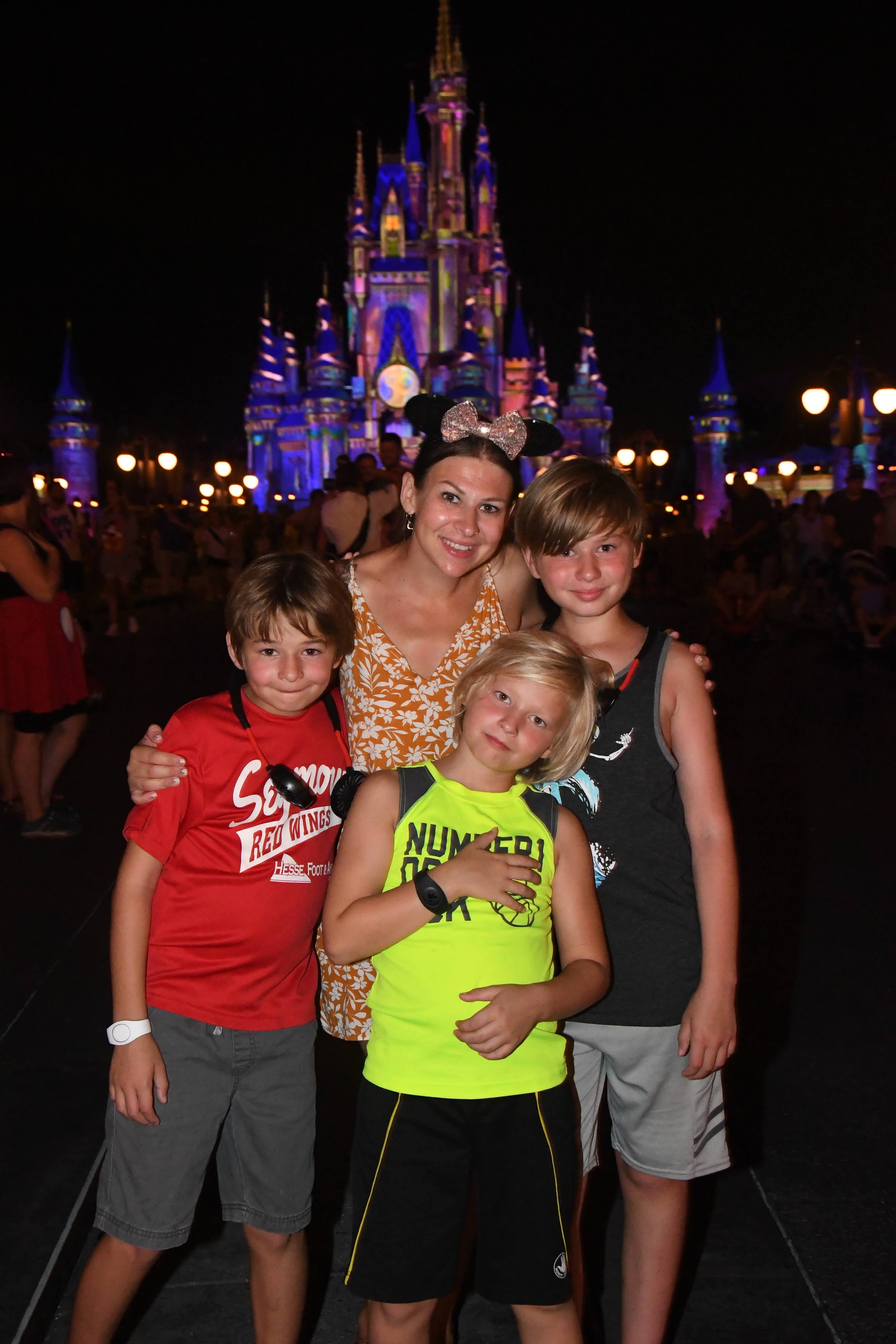Mom of three boys plans a first time disney trip with disney world tips for families. They stand in front of cinderella's castle in walt disney world located in orlando Florida. 