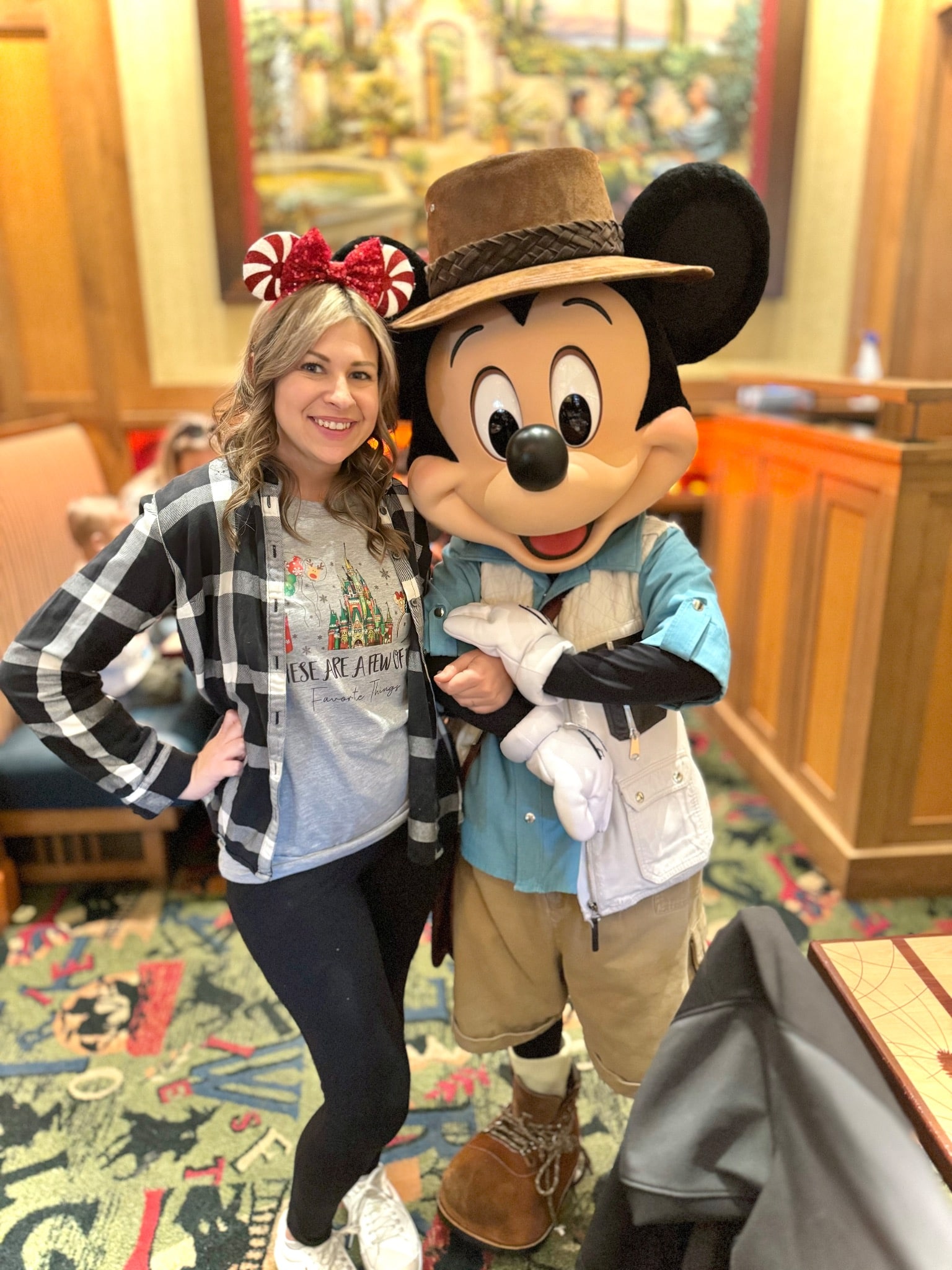 Disney Travel Agent in Disneyland Resort California stands with mickey mouse at a character breakfest. Travel agent with friend like me travel, she wears pepermint mickey ears and a flannel top.
