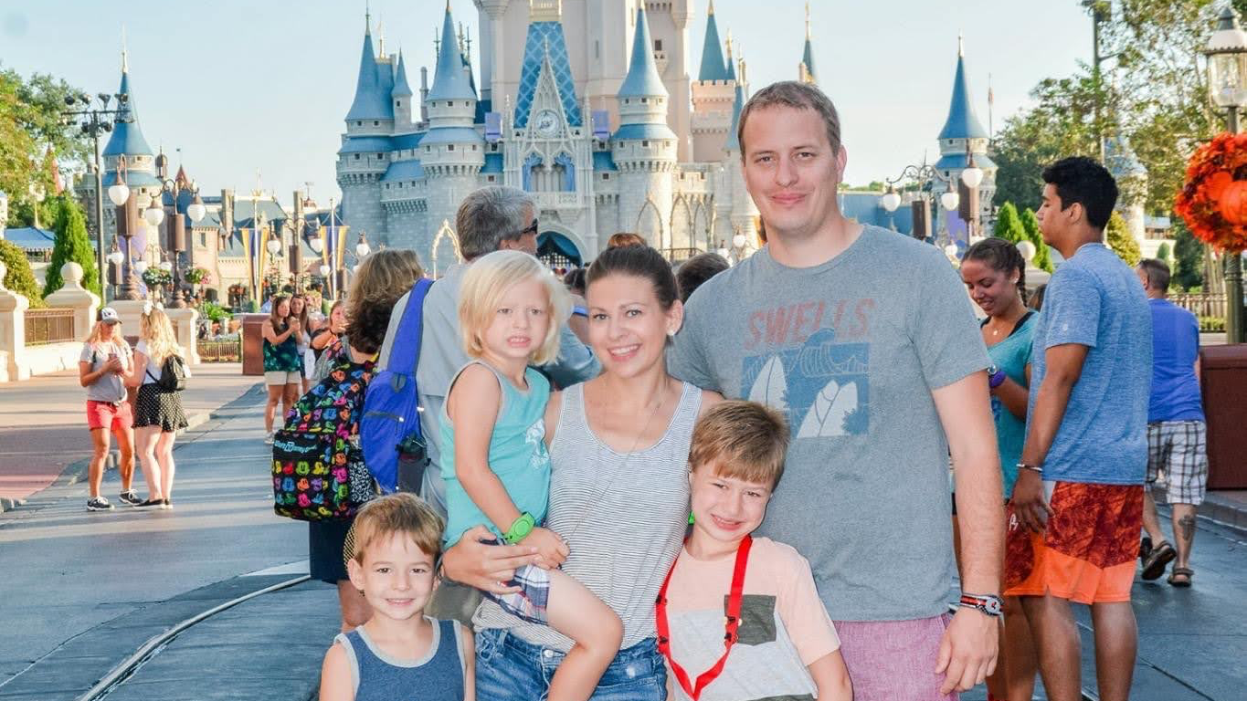 Family photo in front of Cinderella Castle at Magic Kingdom on a sunny day. Taken during a Disney World vacation planned with a travel agent specializing in Disney vacations from Eau Claire, Wisconsin.