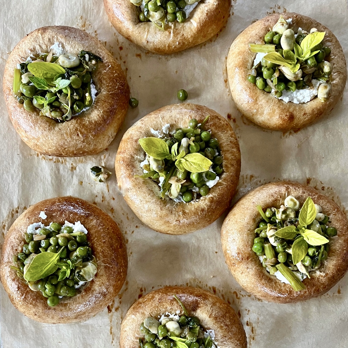 Overhead view of Savoury Brioche Buns topped with whipped feta cheese, peas and broad beans.