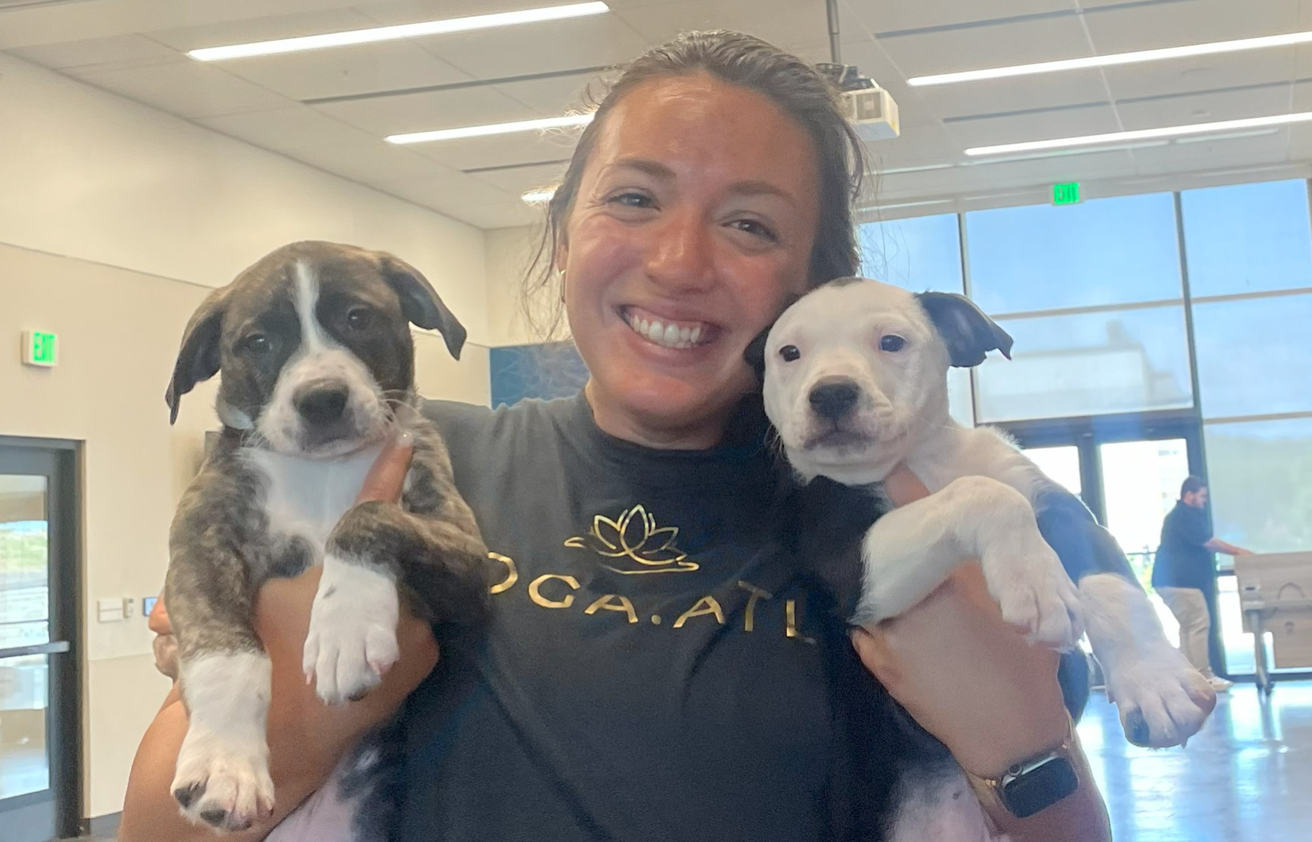 founder of Yoga.ATL, Ali, holding two puppies from puppy yoga
