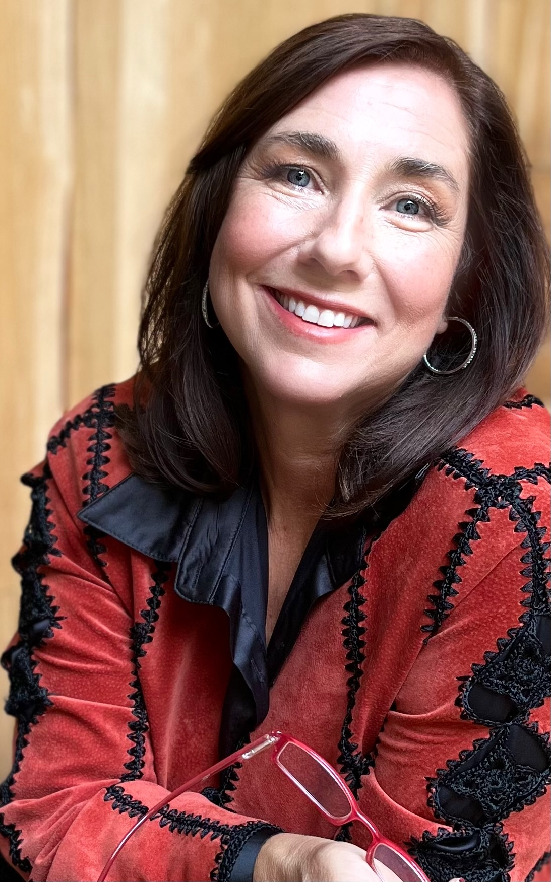 “Yavonne Butcher, author and founder of Fireside Publishing Group, smiling warmly with hands resting under chin, wearing a red and black patterned jacket.”