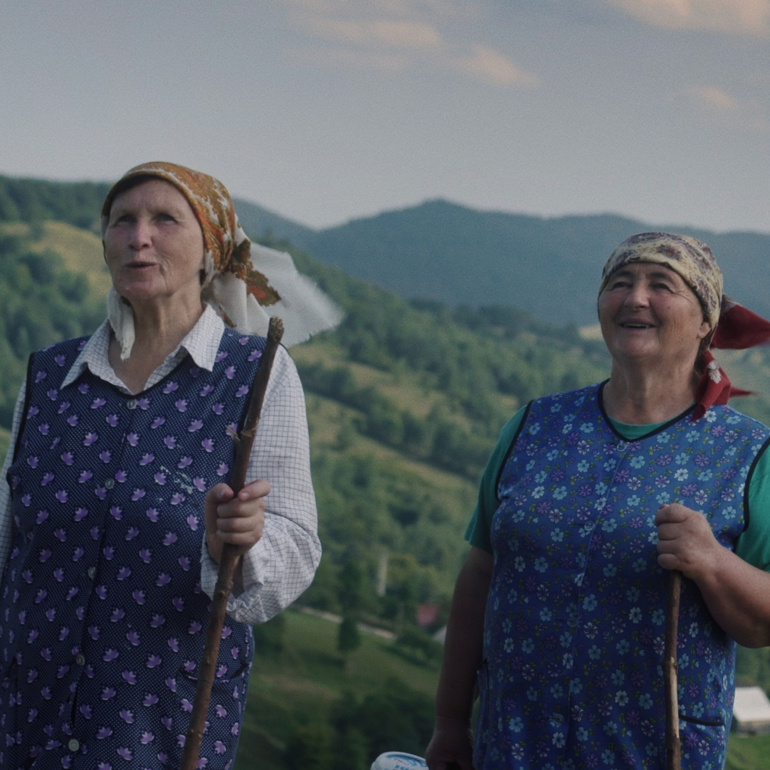 Kadr z filmu przedstawiający postać kobiecą stojącą przy mikrofonie.