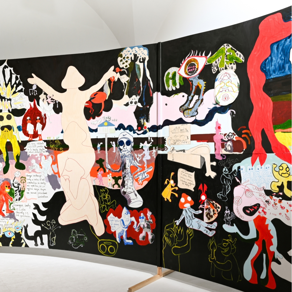 Kadr z filmu przedstawiający postać kobiecą stojącą przy mikrofonie.