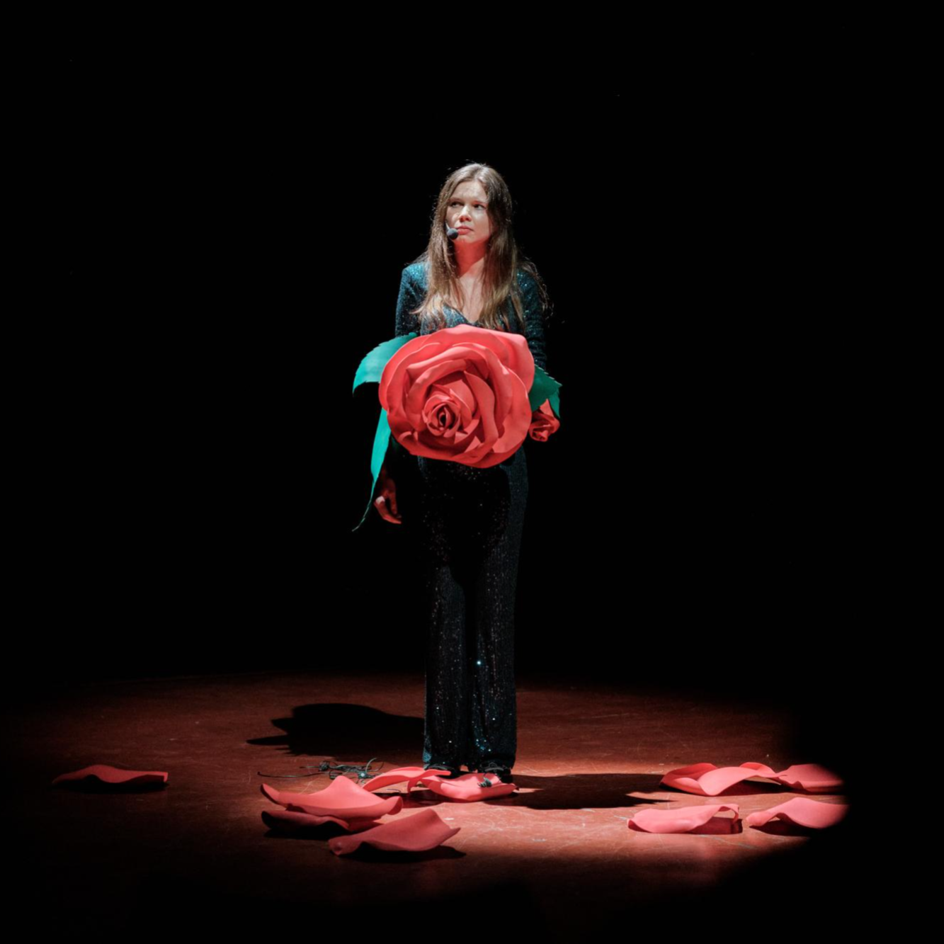 Kadr z filmu przedstawiający postać kobiecą stojącą przy mikrofonie.