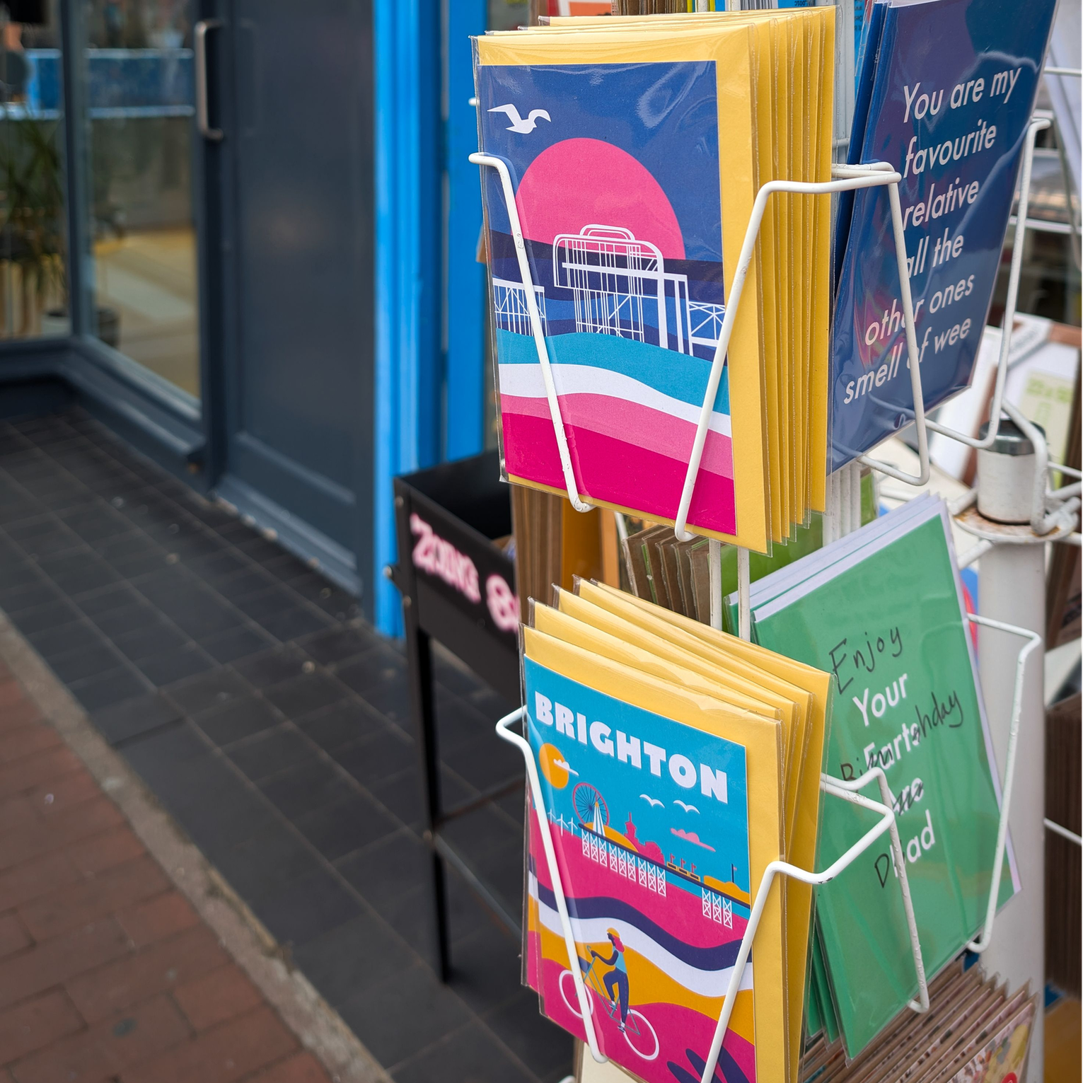 A shelf in a shop filled with colourful brighton and hove products, such as prints, mugs and cards