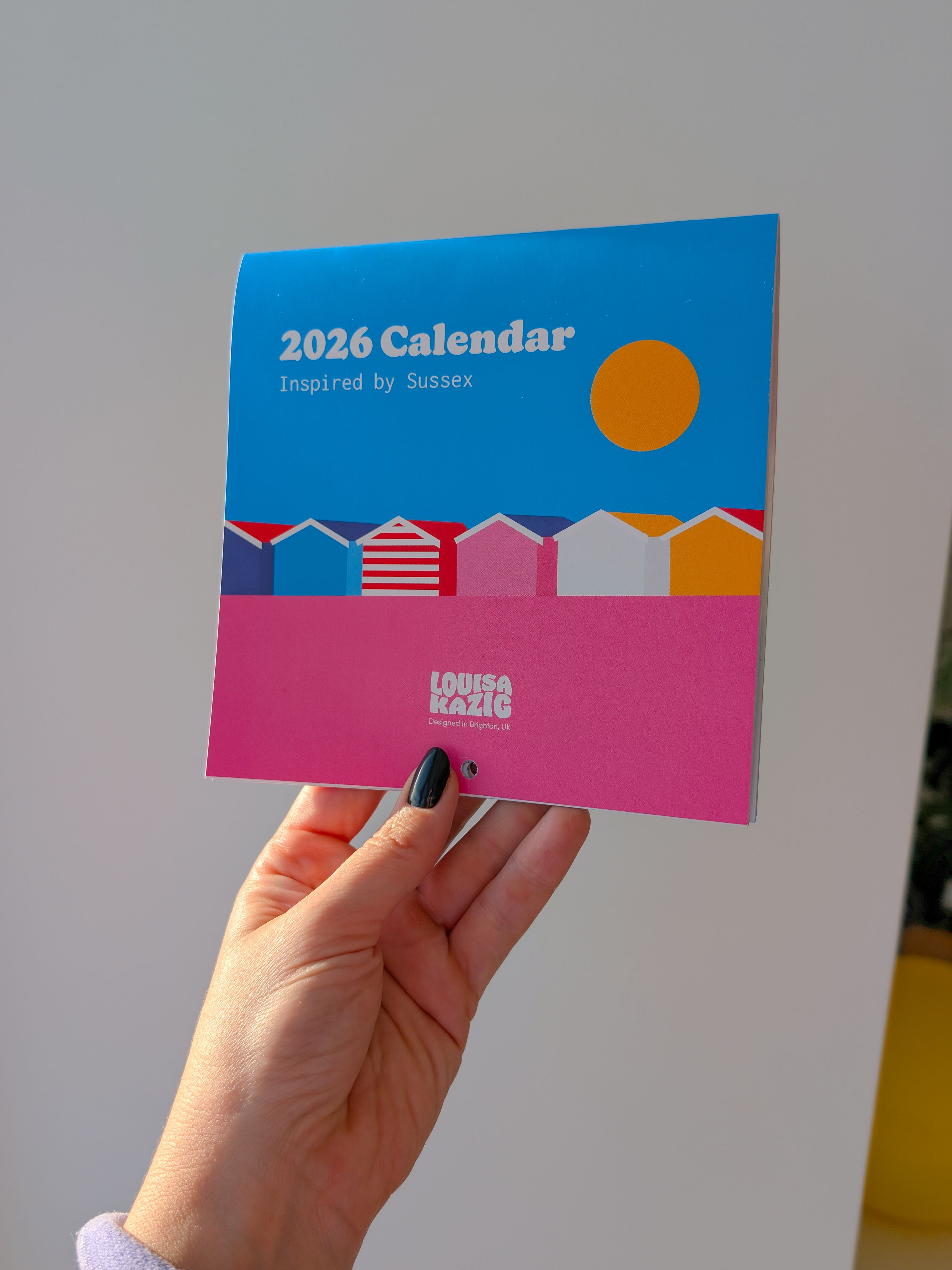 A hand holding a print showing white cliffs, a sunset and seagulls