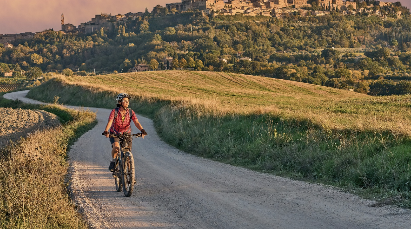 woman bicycling on a road between fields