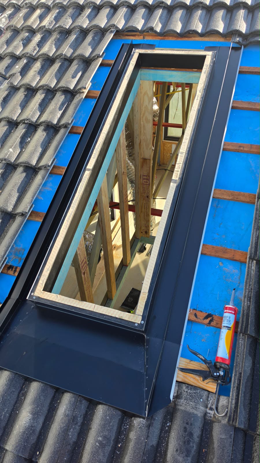 New skylight frame being fitted into a tiled roof