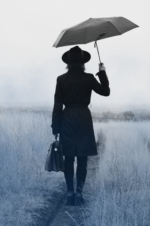 Woman in vintage apparel with an umbrella walking away