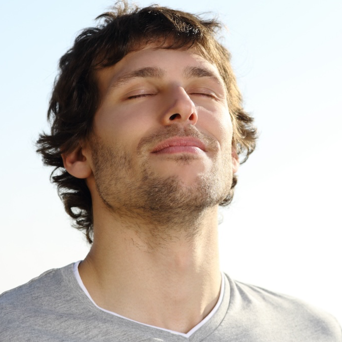 Self Love Mission - a place where people connect around self-love, starting with a gentle introductory breath-work course for people who want to connect more deeply to their true selves, represented by a handsome young man with a peaceful face breathing in the clear air.