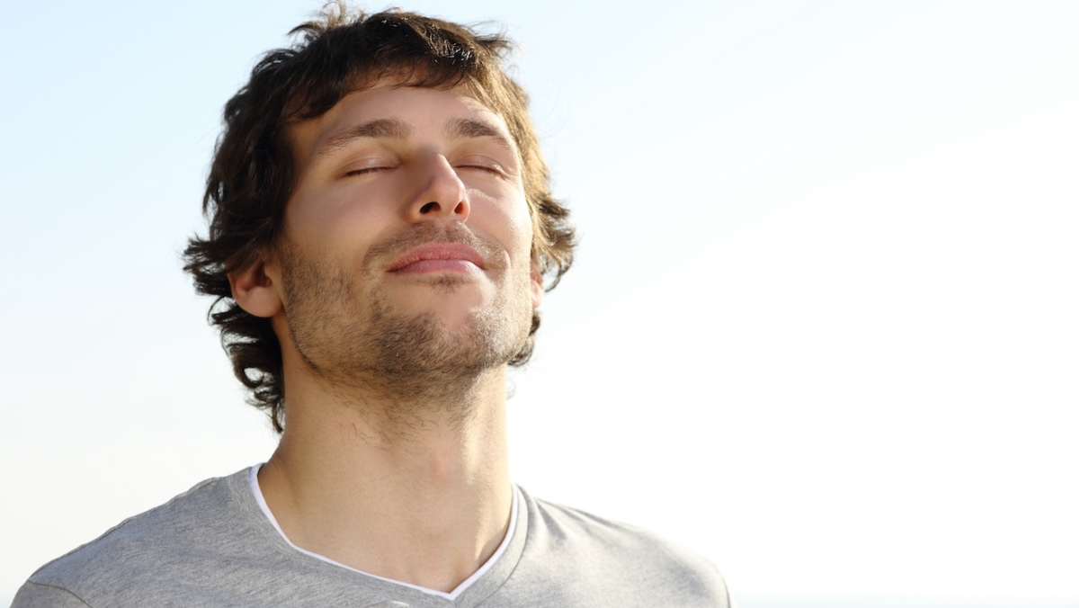 Self Love Mission - a place where people connect around self-love, starting with a gentle introductory breath-work course for people who want to connect more deeply to their true selves, represented by a handsome young man with a peaceful face breathing in the clear air.