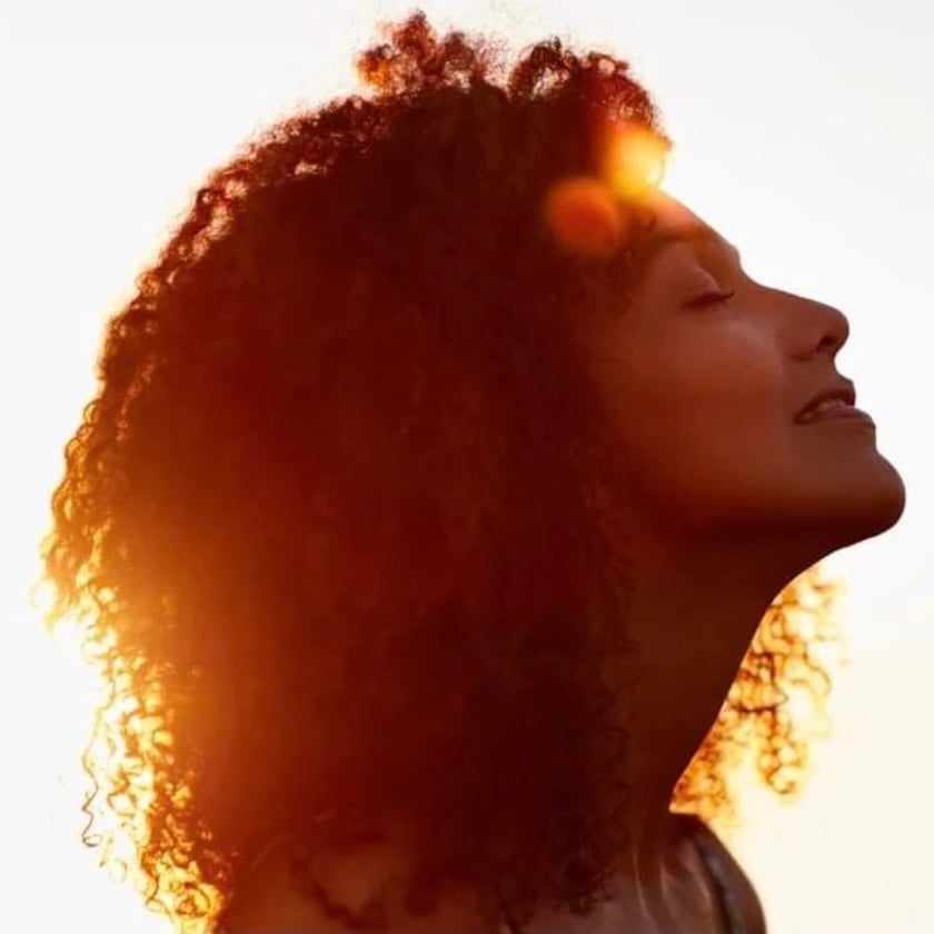 beautiful young woman at golden hour smiling with her eyes closed in self-love and inner peace