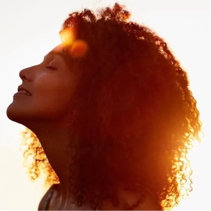 Breathe and Receive - a gentle introductory breath-work course for people who want to connect more deeply to their true selves, re[resented by a beautiful woman in a meditation pose in front of a giant gold and white lotus flower.
