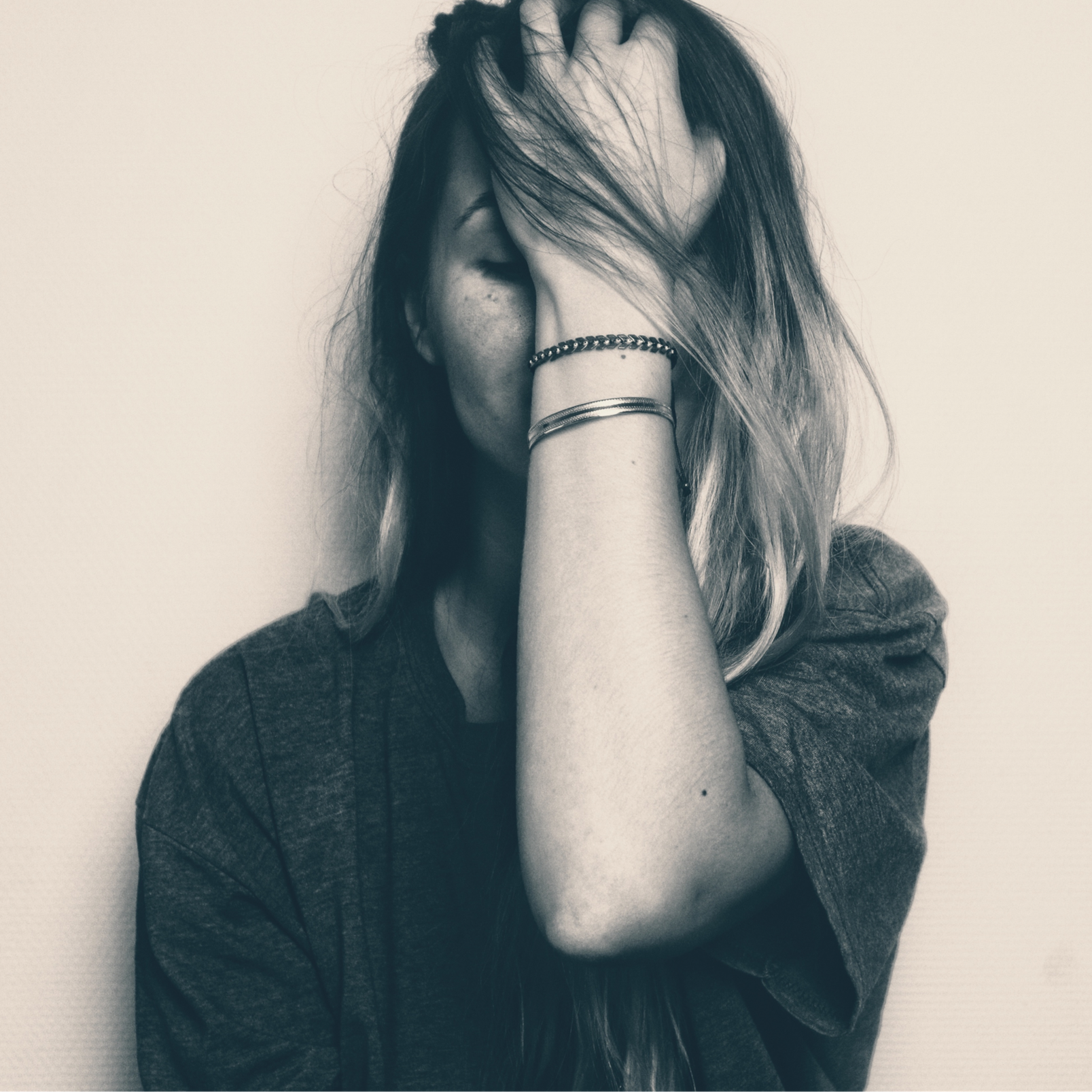 young woman holds her head in her hand in sadness and despair.