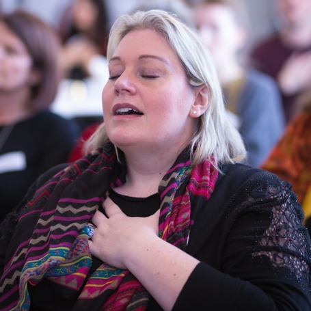 woman holding her hand on her heart with eyes closed looking serene and peaceful in an audience at a self love event with Tara Love Perry