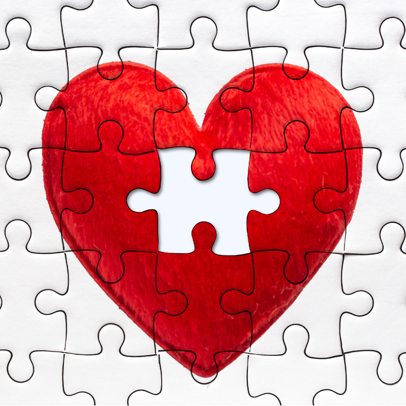 a white jigsaw with a red heart in the centre and the central piece is missing.