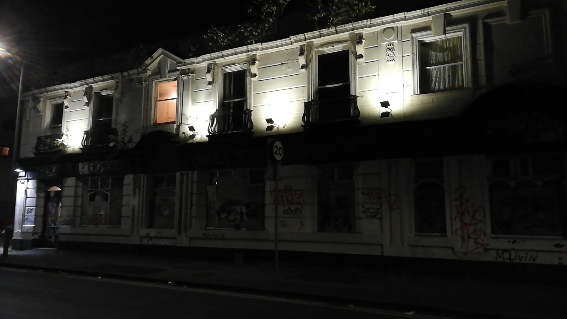 Photo of The Junction Pub on Rolls Crescent at night. There is a light on in one of the windows and the external lights on the building are also lit, illuminating the first floor of the building.