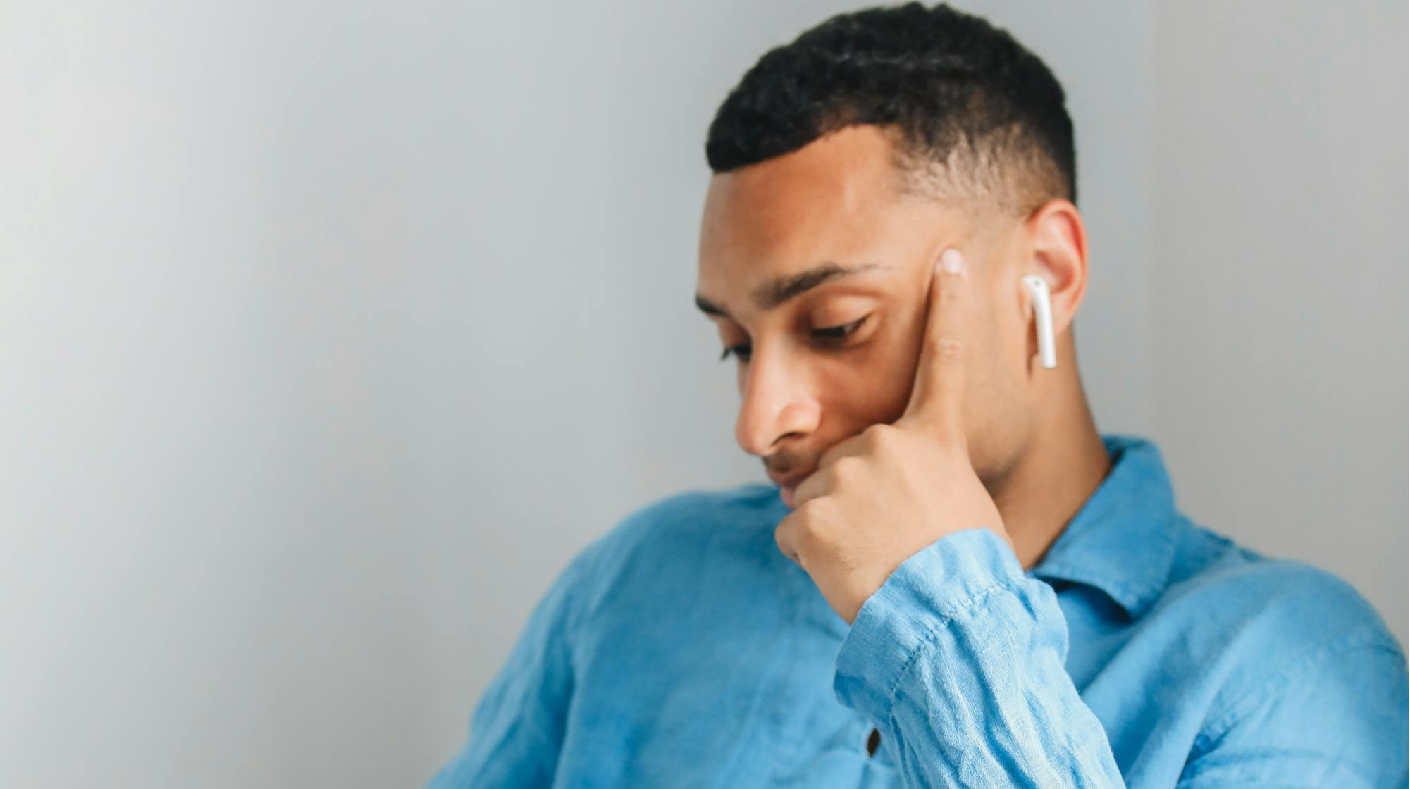 Person liiking down with earphones in ears, seemingly contemplative