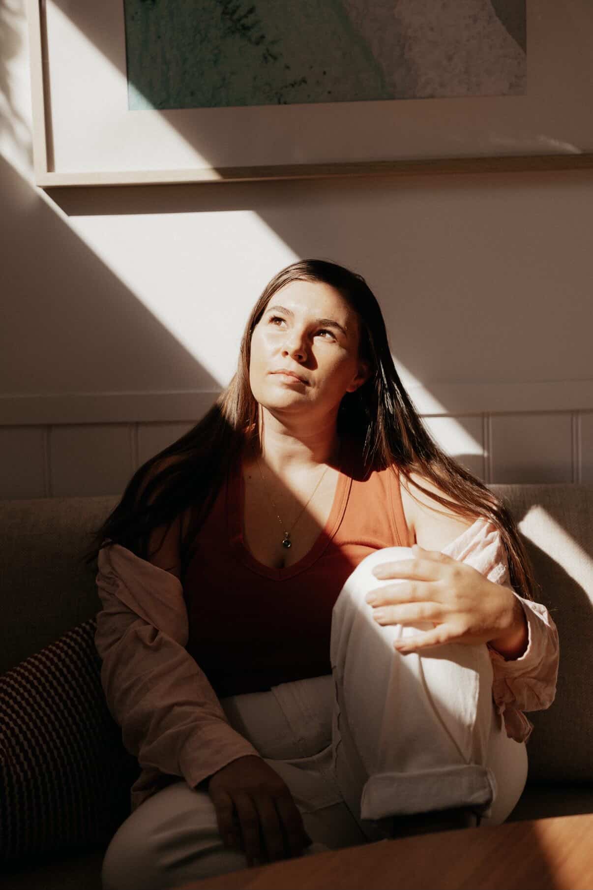 Hannah in profile, smudging with sage smoke rising, caught in window light