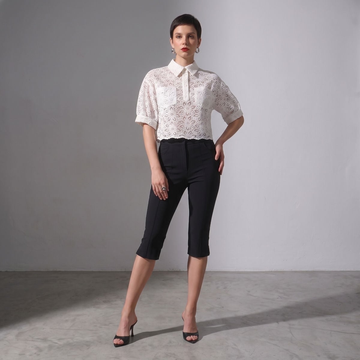 Nowoczesna elegancja: kontrastowy zestaw z białą ażurową bluzką Klara Off White i czarnymi spodniami 3/4.