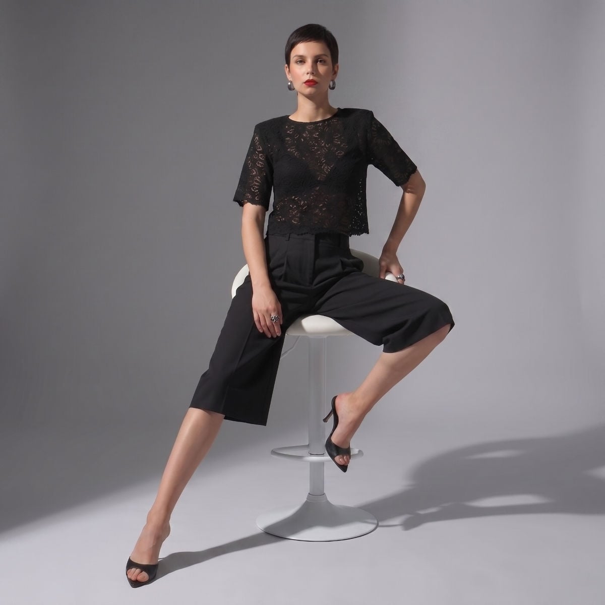 Elegancka damska stylizacja: czarna koronkowa bluzka z krótkim rękawem, czarne spodnie Bermudy Lois Black