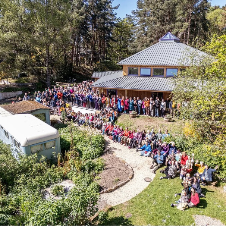 Findhorn Ecovillage building and grounds with crowds of happy people waving.