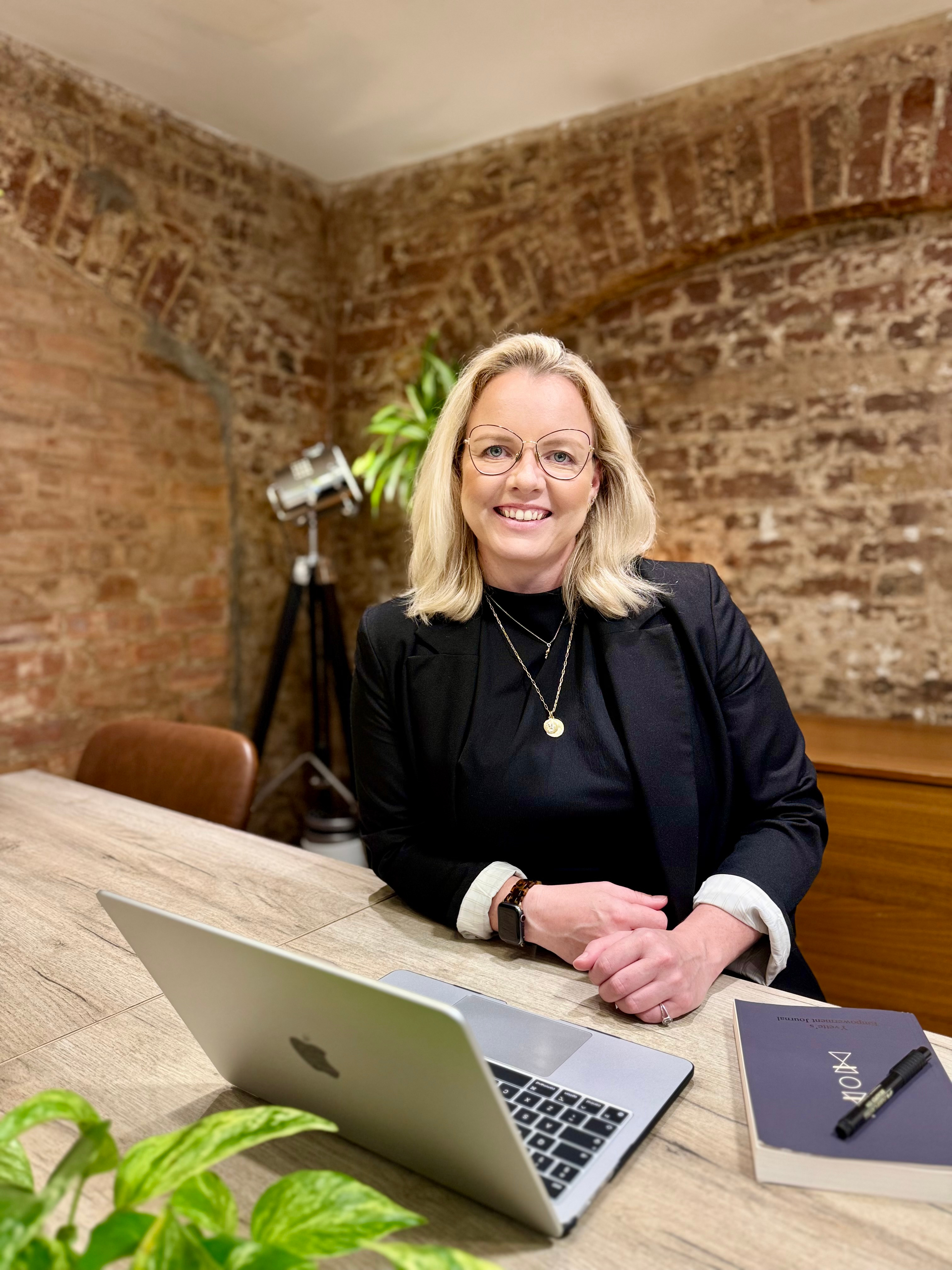 Woman with blonde hair sitting behind a MAC computer