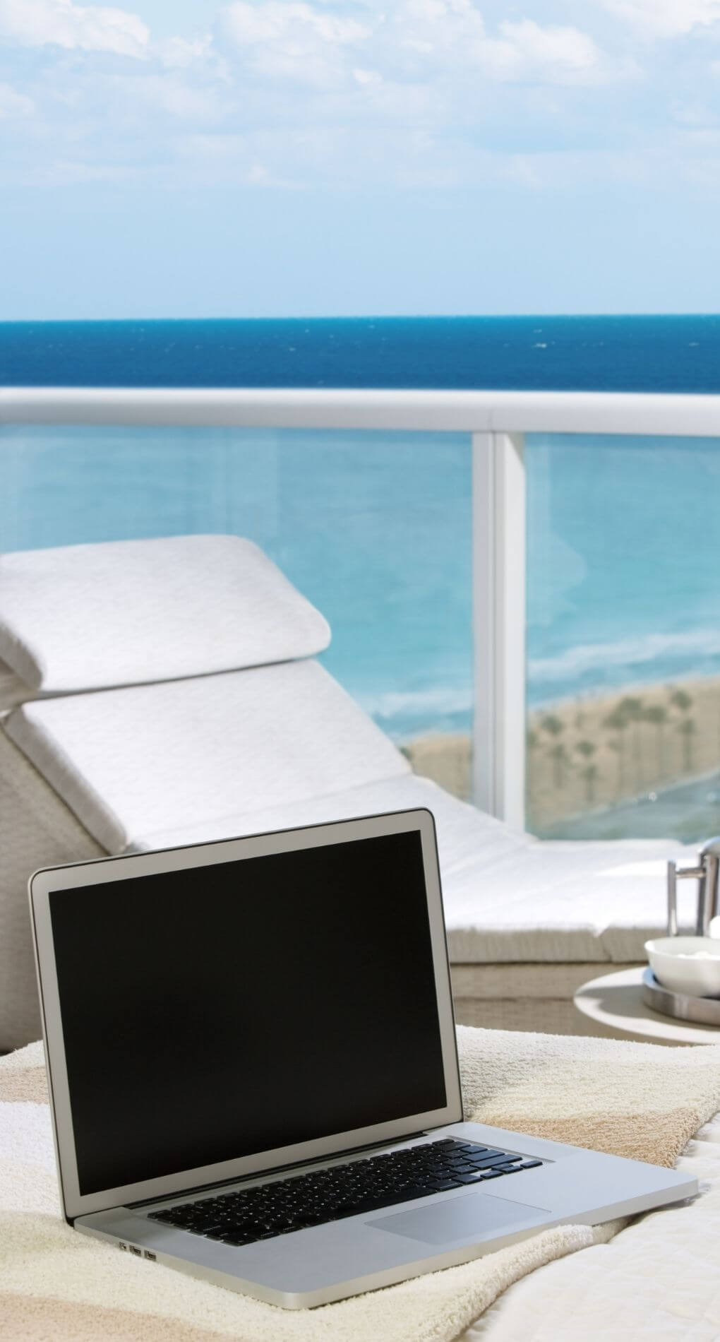 image of a laptop at a resort with a beach view