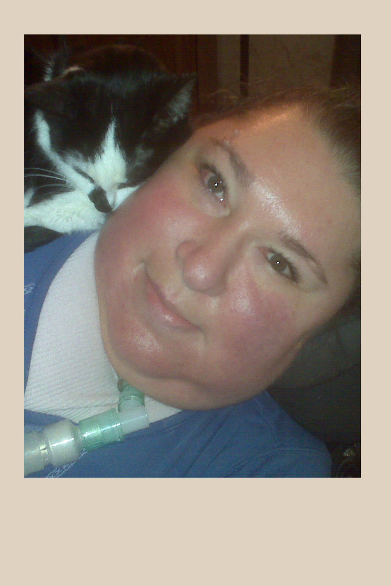 Headshot of Maria Matzki. A young woman smiling. She has a black and white cat resting on her shoulder as Maria is reclined.