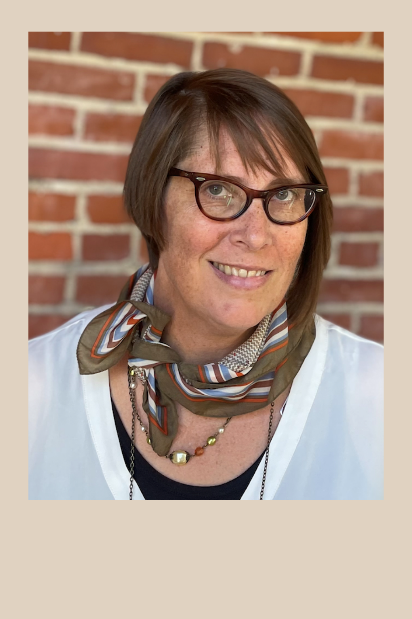 Headshot of Brenda Vitale. Middle aged woman with short brown hair wearing glasses, a scarf and necklace.