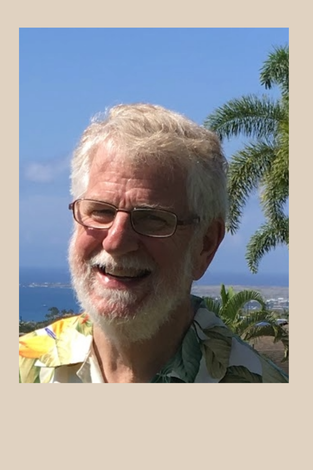 Headshot of Merle Edwards-Orr. Recent retired man with white/red hair and a bear. He also wears glasses. The photo looks to be taken at the beach.