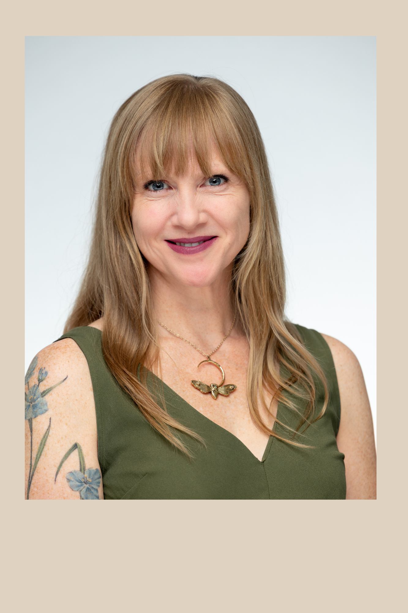 Photo of Bevin Croft. Young man standing. Has long blond hair and a green sleeveless shirt.  Has a tattoo on right arm