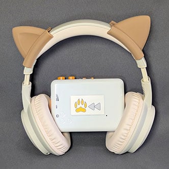 Custom white cassette player with Paws & Rewind logo, paired with beige cat ear headphones