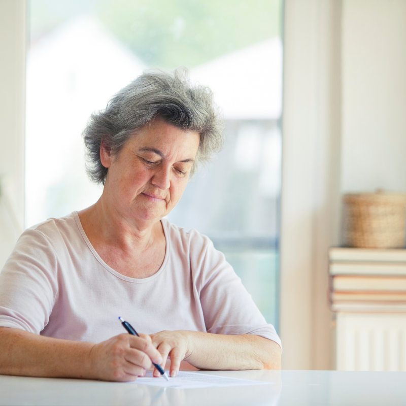 Older woman writing a letter at a window - Your Final Matters Legacy Letter Writing workshop