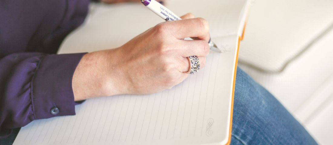A woman writing in a notebook, tracking her cycle and sleep