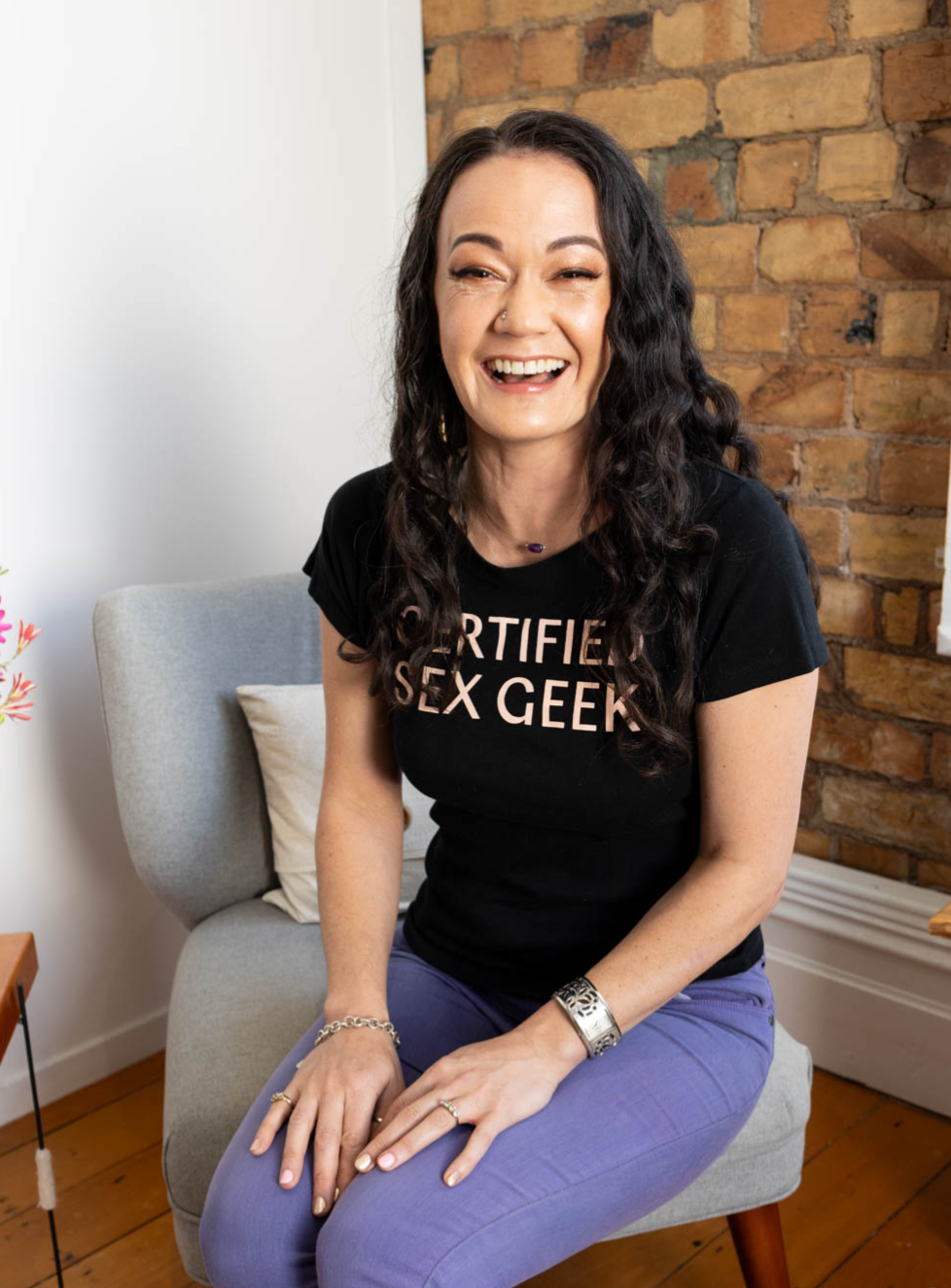 Smiling somatic sexologist wearing a Certified Sex Geek shirt, looking confidently at the camera