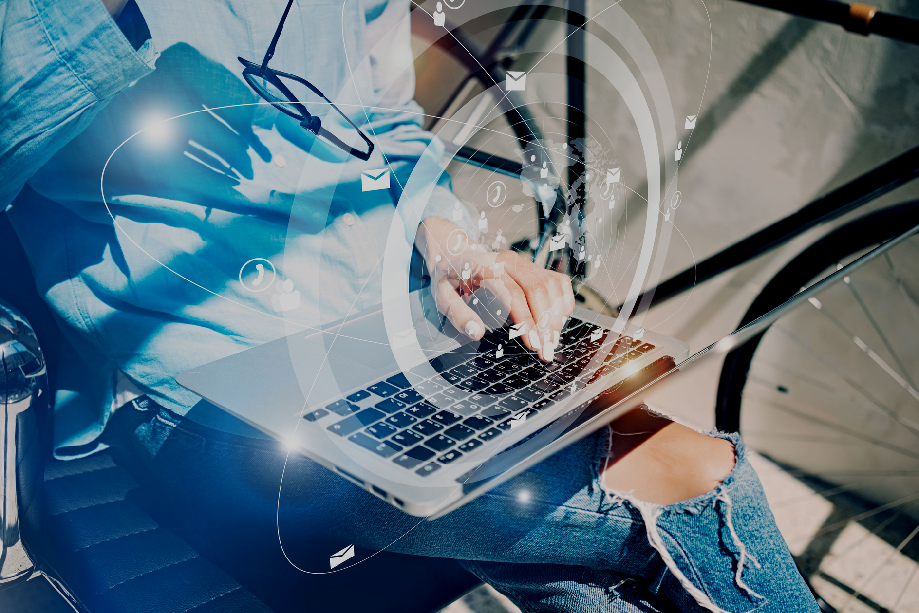 Person typing on a laptop while sitting outdoors, overlaid with digital icons representing app features and notifications