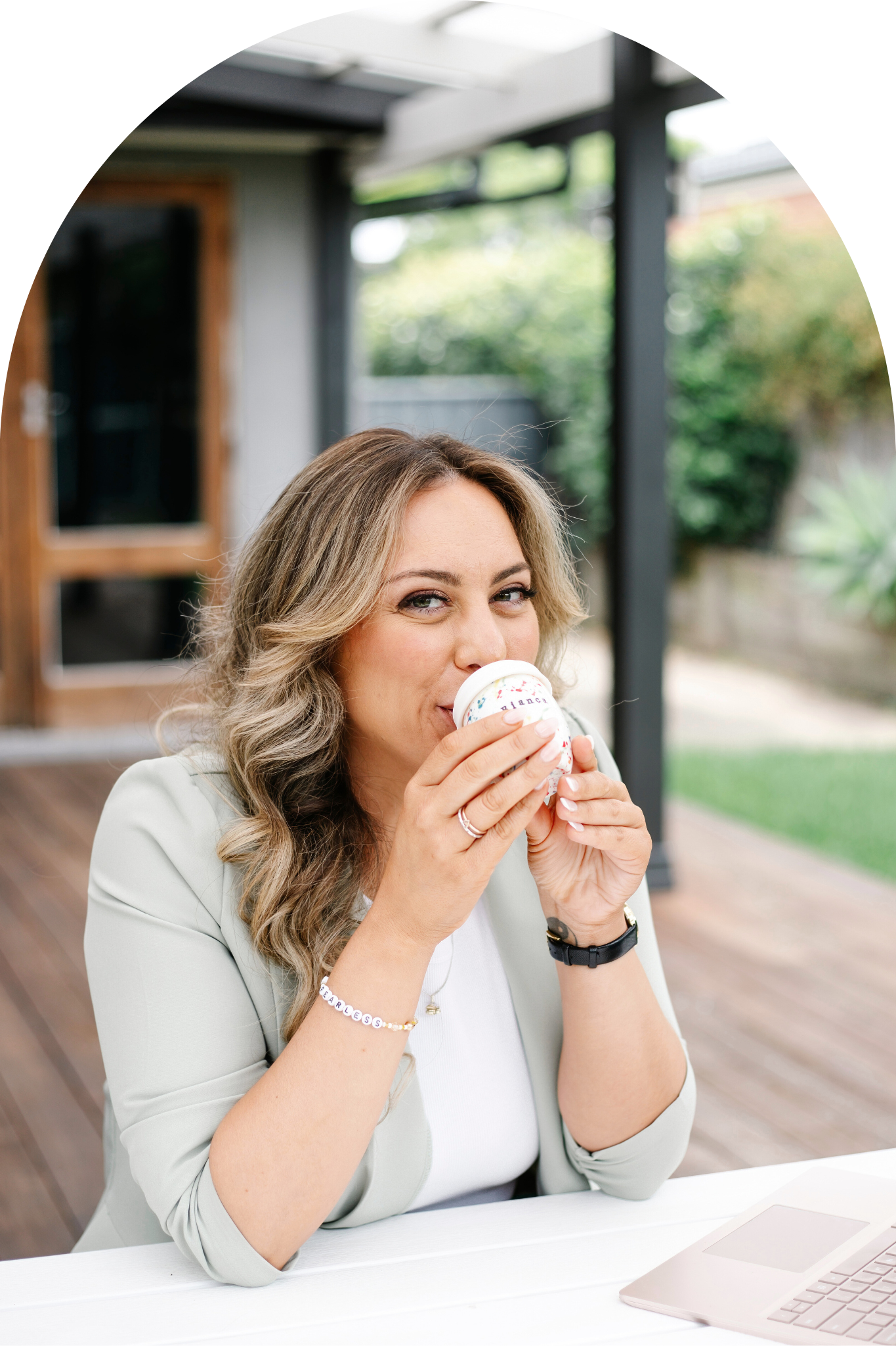 woman sitting at table drinking from reusable coffee cup