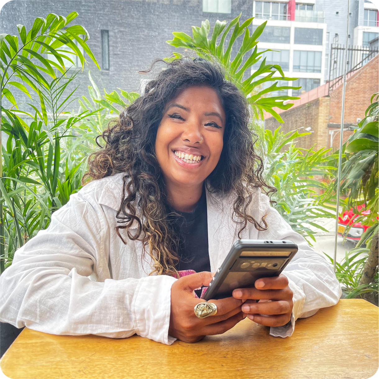 Farhana Aboo smiling while holding a phone, encouraging visitors to get in touch for coaching support