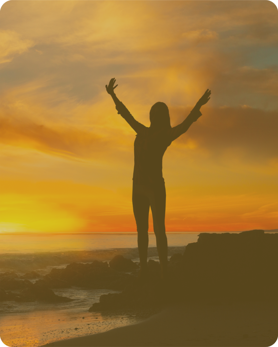 A woman standing on a mountain peak at sunset with arms raised, symbolising empowerment, transformation and personal growth.