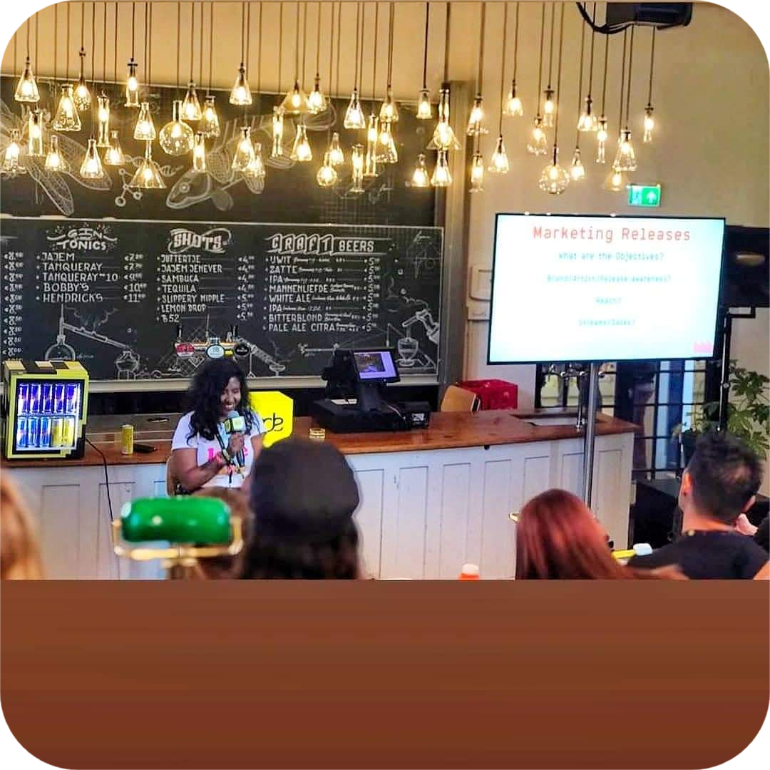 Farhana Aboo in a coaching conversation with a client, sitting at a desk in a relaxed, informal setting