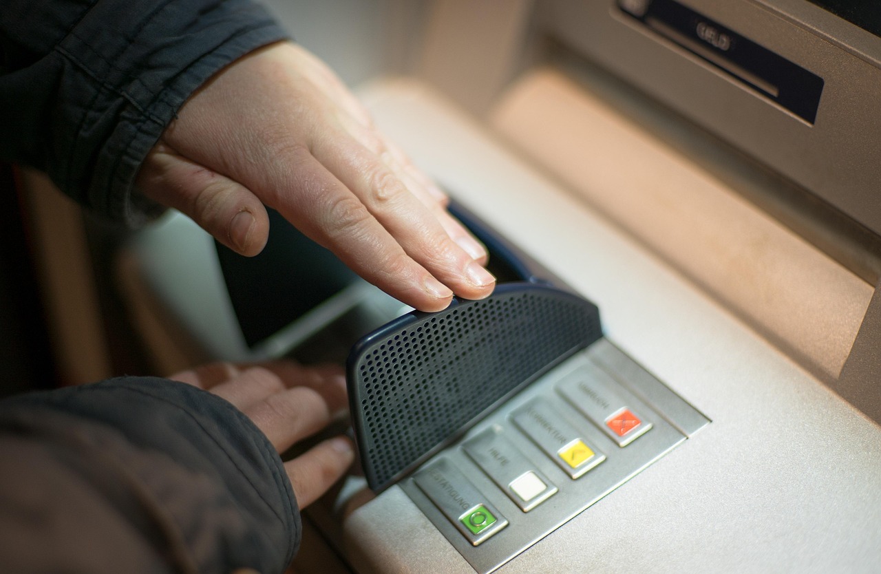 Hand covering ATM keypad while entering PIN to block hidden cameras and prevent skimming