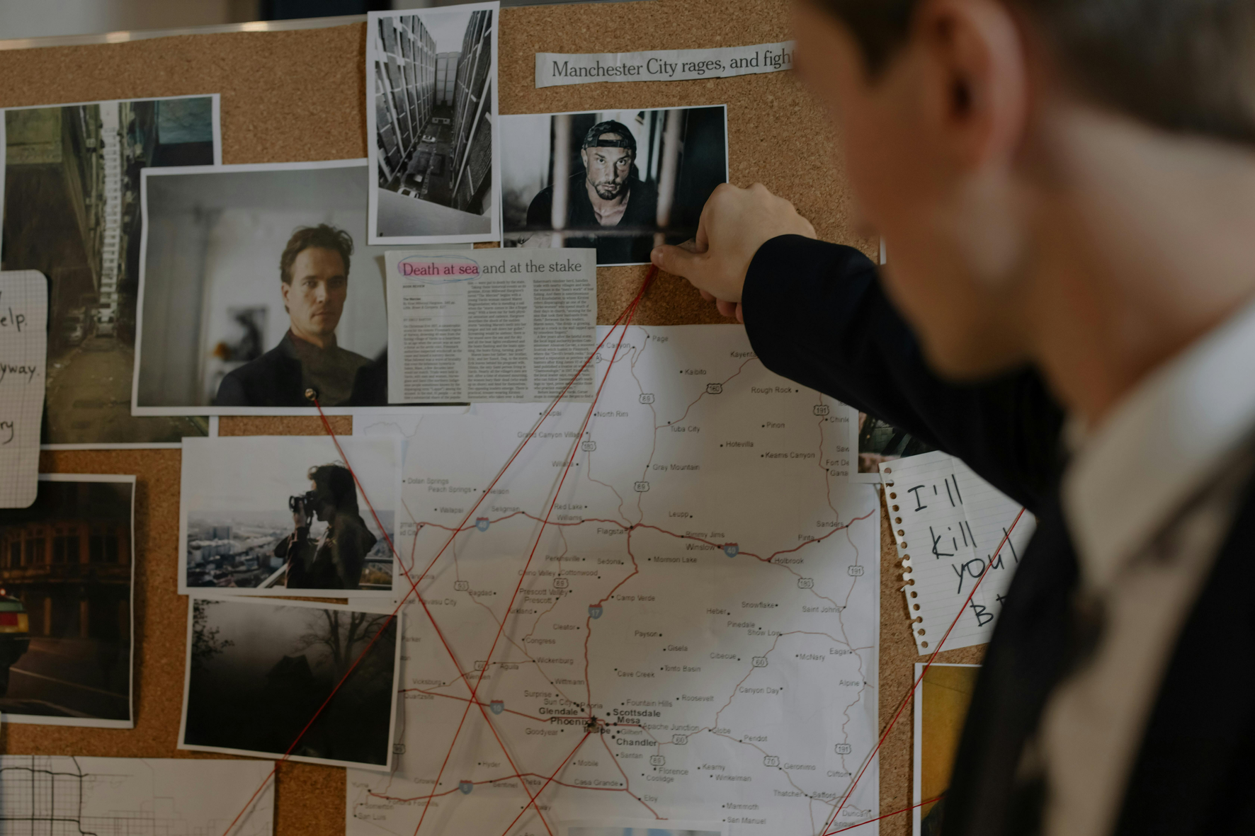 Detective pointing at crime board with photos and strings