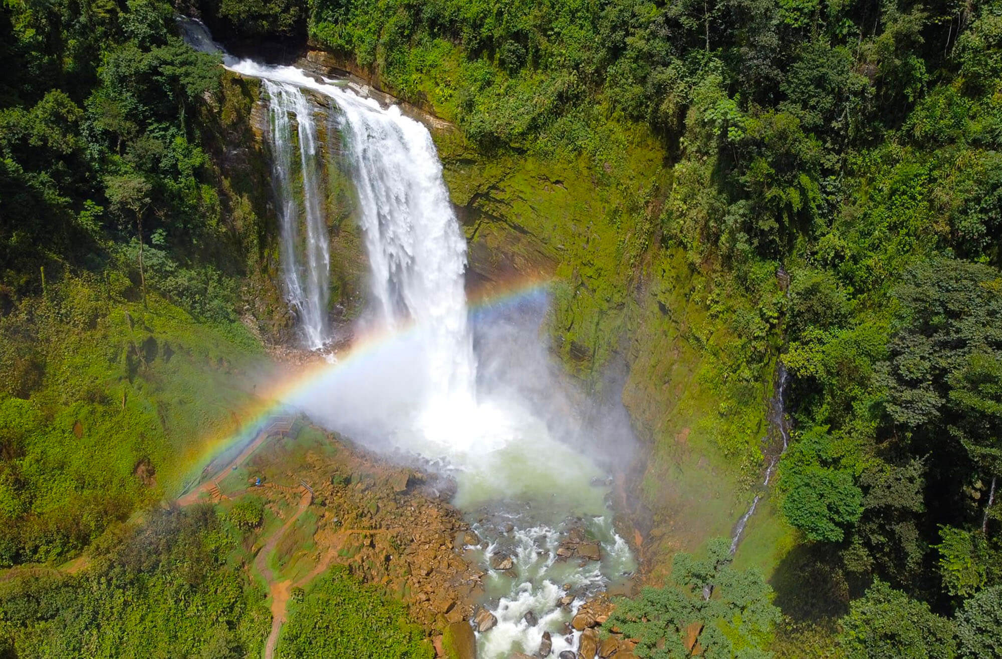 Aerial view of spectacular waterfall with rainbow mist in tropical forest