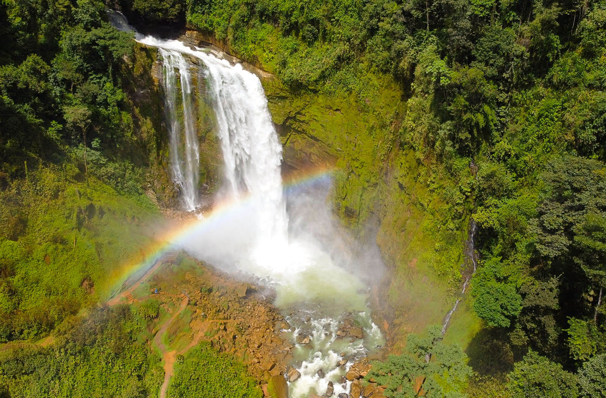Mountain waterfall with rainbow through rainforest cliffs
