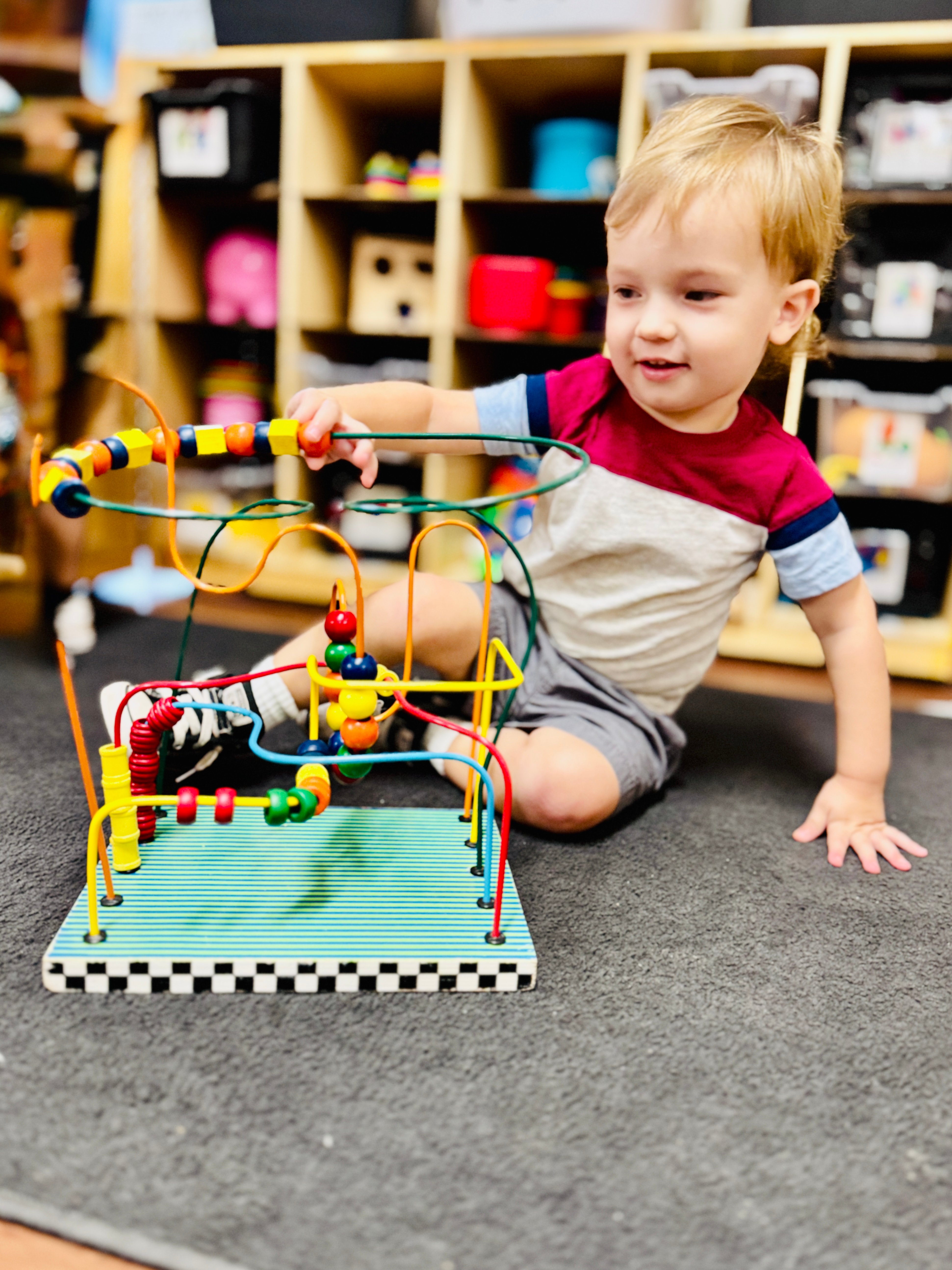 Toddler exploring with a bead maze at school in Boerne.