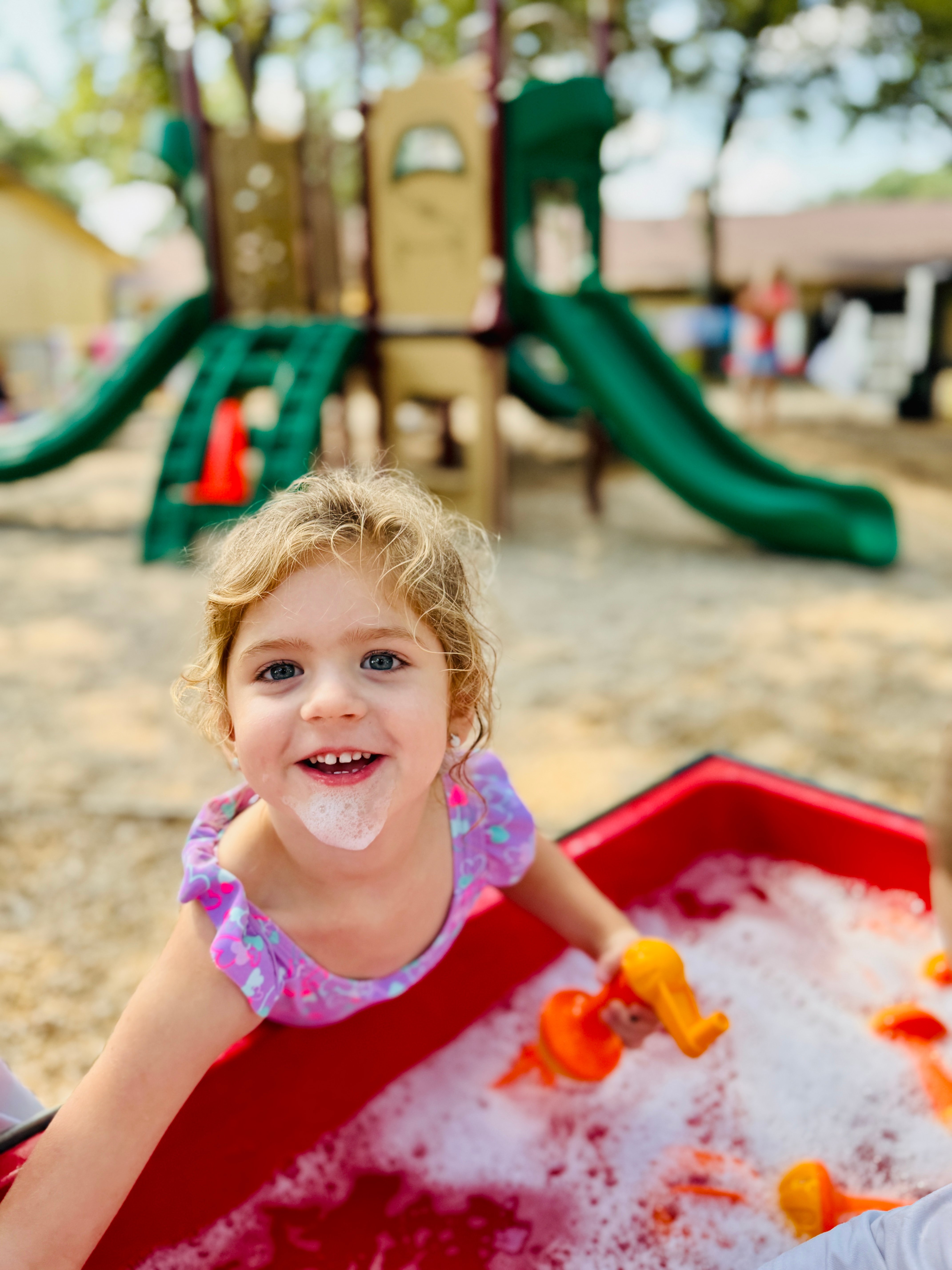 Preschool child engaged in water play on the playground at school.